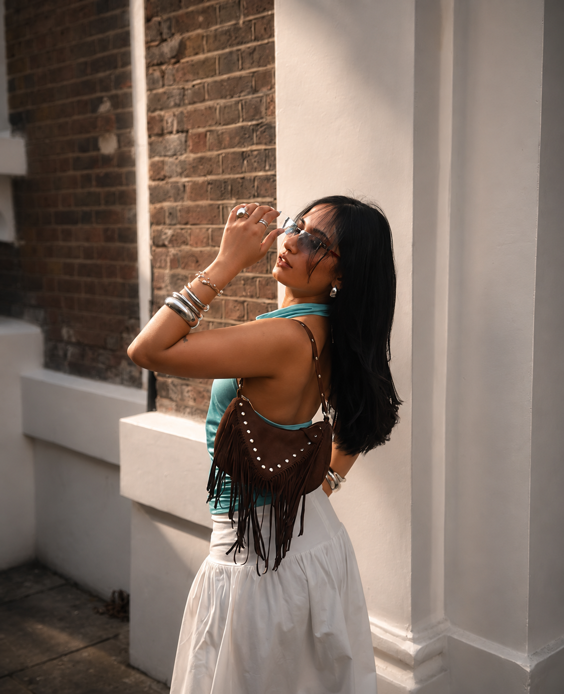Methulie Jayawickrama photographed on a London street in a white skirt and fringed bag